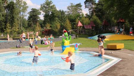 Children play in the paddling pool outside at holiday park Molecaten Park Landgoed Ginkelduin