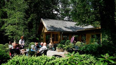 People are sitting on the terrace of the canteen of holiday park Molecaten Park Landgoed Molecaten