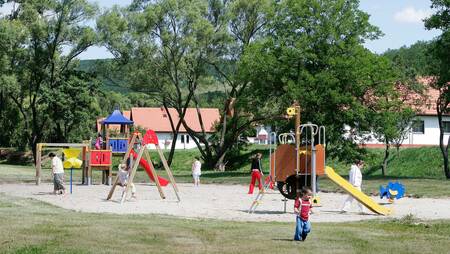 Children play in the playground of the small-scale holiday park Molecaten Park Legénd Estate