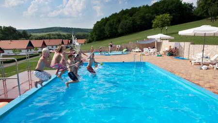 Children jump into the outdoor pool of holiday park Molecaten Park Legénd Estate