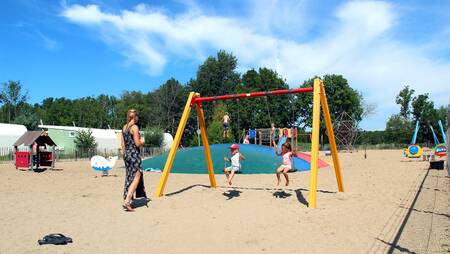 Children on a swing in a playground at holiday park Molecaten Park Rondeweibos