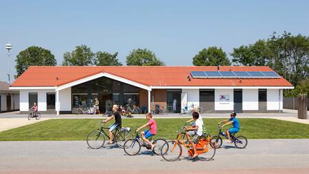Children cycle in front of the supermarket of holiday park Molecaten Park Rondeweibos