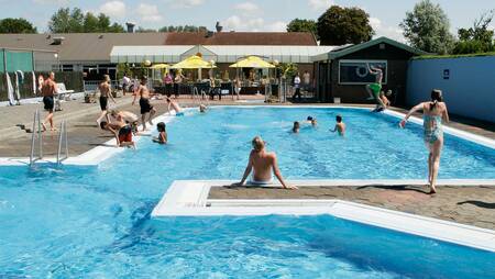 People swim in the outdoor pool of holiday park Molecaten Park Rondeweibos
