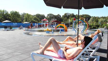 People on sun loungers at the outdoor pool of Molecaten Park Rondeweibos