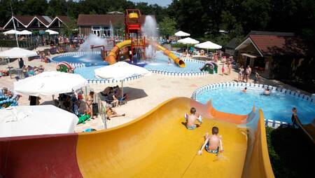 Children slide down a wide slide in the outdoor pool of holiday park Molecaten Park 't Hout