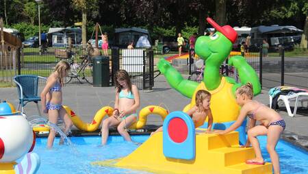 Children play in the paddling pool outside at holiday park Molecaten Waterbos