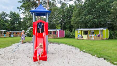 Children play in a small playground between chalets at holiday park Molecaten het Landschap