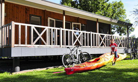 Boy with a canoe in front of a chalet at the Moulin de Hotton holiday park