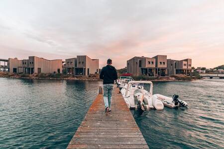 Man walks past boats at a jetty at the Oasisparcs Oasis Punt West holiday park