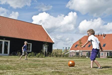 Children playing football between holiday homes at Oosterscheldepark De Stelhoeve