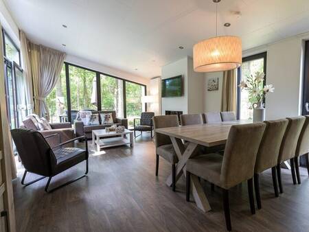 Living room with large dining table in a holiday home at Park Berkenrhode holiday park