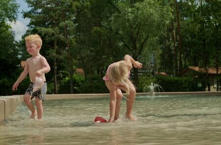 Children splashing in the outdoor pool of holiday park Park Molenheide