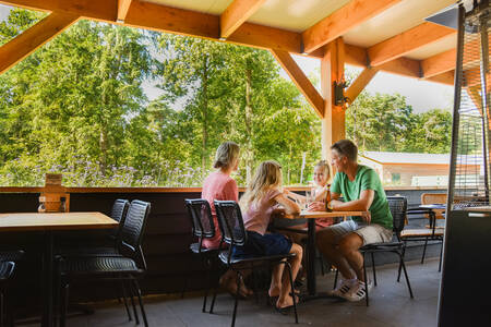 Family eating on the covered terrace of the restaurant at holiday park RCN De Noordster