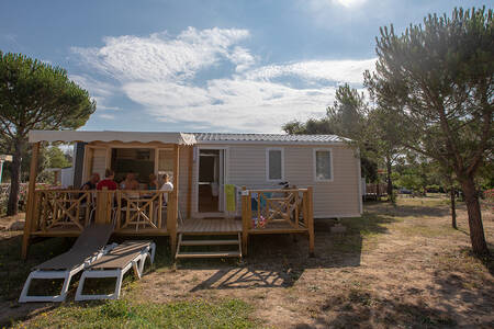Family on the porch of a mobile home type Monaco at holiday park RCN Domaine de la Noguière