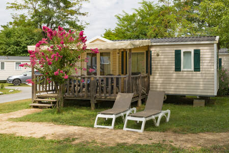 A mobile home with a covered veranda and sun loungers at the RCN La Bastide en Ardèche holiday park