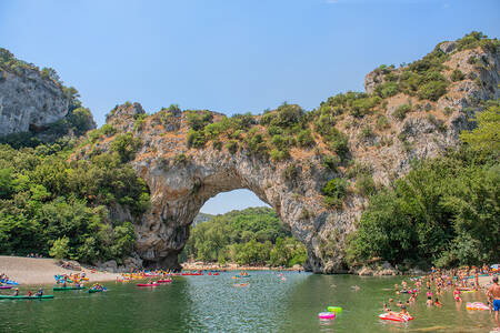 People on the water and beach of the river Ardèche next to holiday park RCN La Bastide en Ardèche