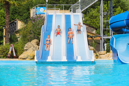 Children slide down a wide slide in the outdoor pool of holiday park RCN Le Moulin de la Pique