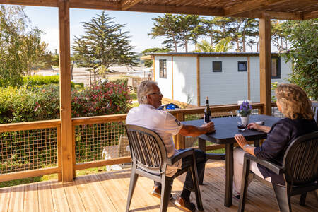 A couple is sitting on the veranda of a mobile home at the RCN Port l'Epine holiday park