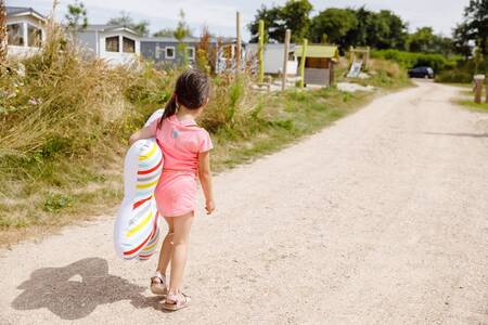 Girl walks along a path past chalets at the RCN Toppershoedje holiday park