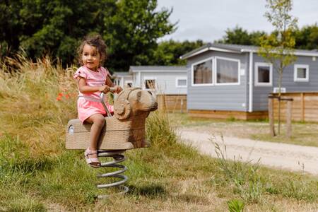 Girl on a seesaw near chalets at the RCN Toppershoedje holiday park