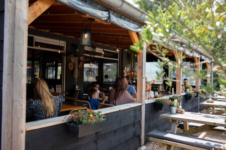 People eating on the covered terrace at the restaurant at the RCN Toppershoedje holiday park