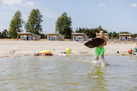 Boy runs through the water of the Veluwemeer at holiday park RCN Zeewolde