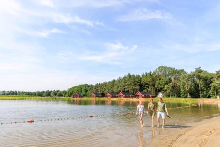 Family walks through the water of the lake at holiday park RCN de Flaasbloem