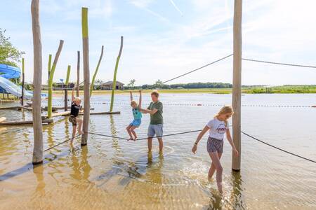 Children play on playground equipment in the water at holiday park RCN de Flaasbloem