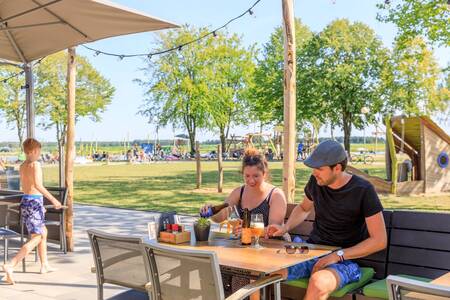 Couple eat on the terrace of Brasserie 't Smokkelstrand at holiday park RCN de Flaasbloem