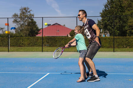 Father and daughter playing tennis on the tennis court of holiday park RCN de Potten