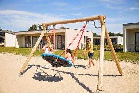 children on a swing in a playground at holiday park RCN de Schotsman