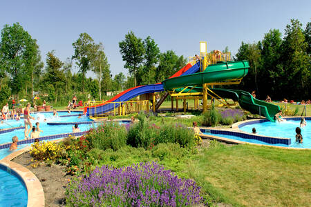 People in the outdoor pool with large slides at holiday park RCN de Schotsman