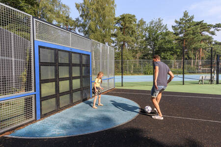 Father and daughter play football on the playing field at holiday park RCN het Grote Bos