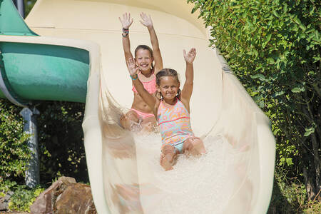Children slide down a large slide in the outdoor pool at holiday park RCN la Ferme du Latois