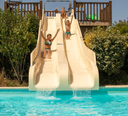 Children slide down the slides in the outdoor pool of holiday park RCN la Ferme du Latois