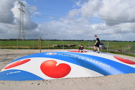 Children jump on an air trampoline in a playground at Recreatiepark Tusken de Marren