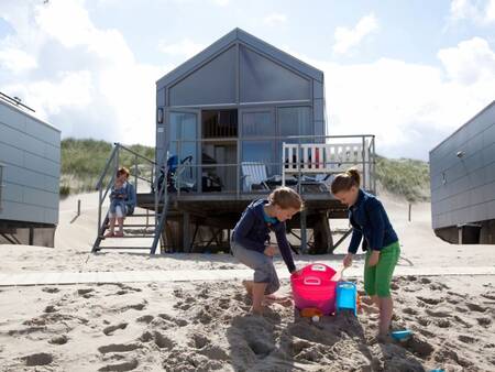 Children play in the sand in front of a Beach House at Roompot Strandhuisjes Julianadorp