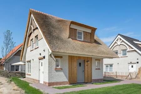 Detached holiday home with a thatched roof at the Roompot Beach Resort Nieuwvliet-Bad . holiday park