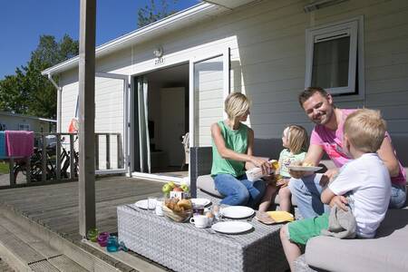 Family eating on the veranda of a chalet at the Roompot Beach Resort holiday park