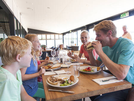 Family eating at a beach pavilion near Roompot Strandhuisjes Julianadorp