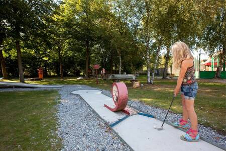 Girl plays golf on the mini golf course of holiday park Roompot Bospark Lunsbergen