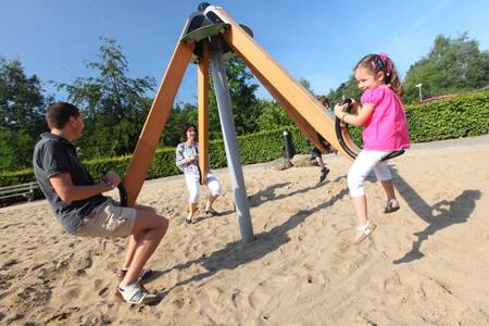 A family is playing in a playground at the Roompot Bospark de Schaapskooi holiday park