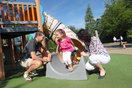 Children slide down the slide in a playground at holiday park Roompot Bospark de Schaapskooi