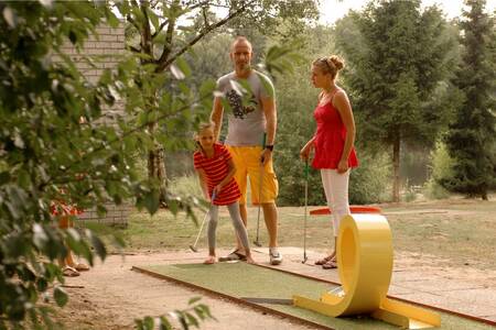 Family playing golf on the mini golf course at Holiday Park Roompot Bospark 't Wolfsven