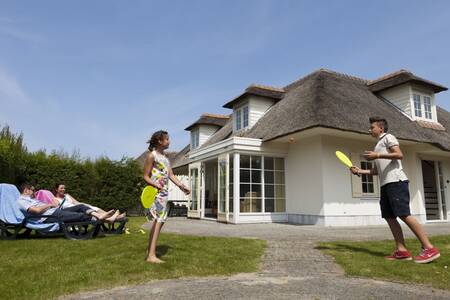Family in the garden of a holiday home with a thatched roof at the Roompot Buitenhof Domburg