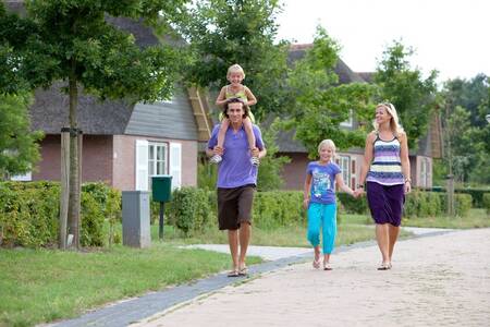 Family walks in front of holiday homes at the Roompot Buitenplaats De Hildenberg holiday park