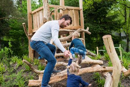 Father with children in a wooden playground at the Roompot Bungalowpark Hoenderloo holiday park