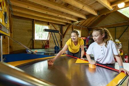 Mother and daughter play air hockey at the Roompot Château des Marais holiday park
