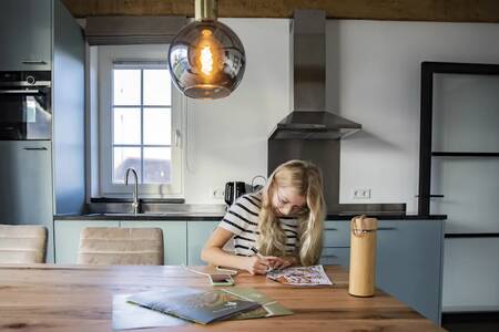 Girl at the table in the kitchen of a holiday home at the Roompot De Heihorsten holiday park