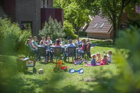 Family sitting in the garden of a holiday home at the Roompot De Katjeskelder holiday park